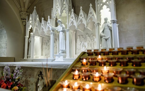 St. Patrick's Cathedral interior with statues and lit votive candles.