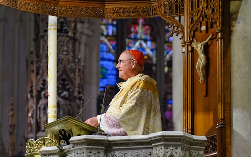 Clergy member speaking at St. Patrick's Cathedral pulpit during audioguided tour.