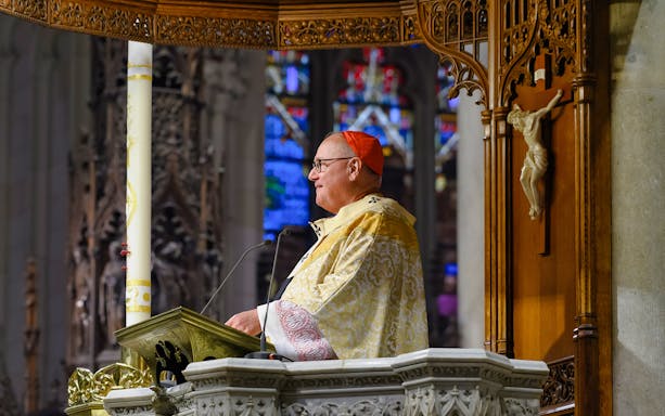 Clergy member speaking at St. Patrick's Cathedral pulpit during audioguided tour.