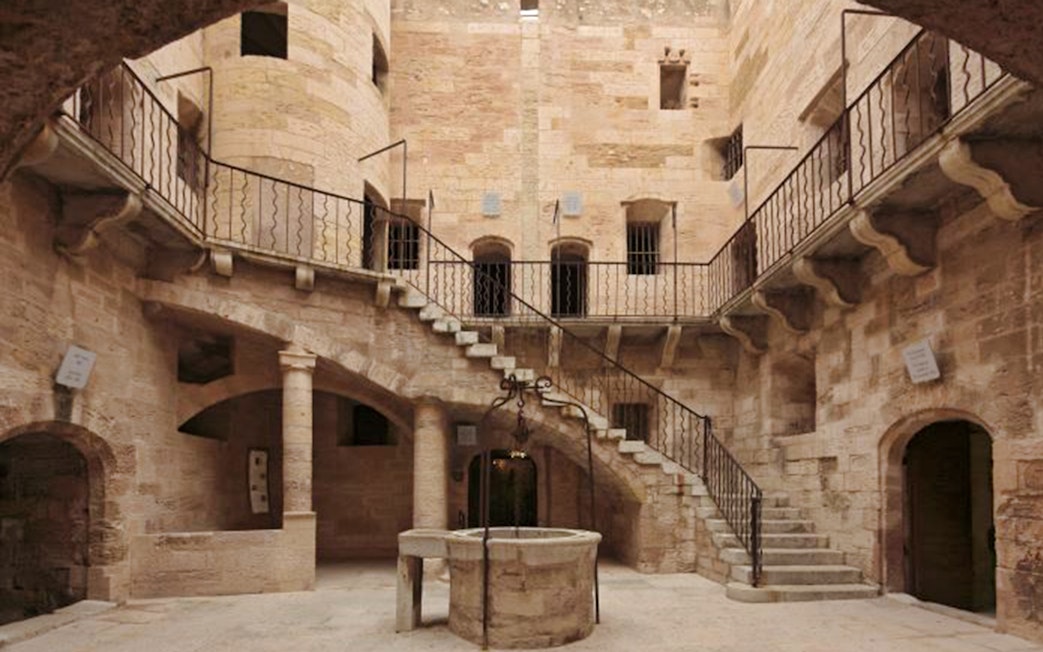 Château d’If courtyard with stone staircase and central well in Marseille, France.