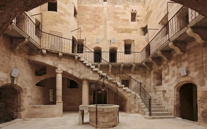 Château d’If courtyard with stone staircase and central well in Marseille, France.