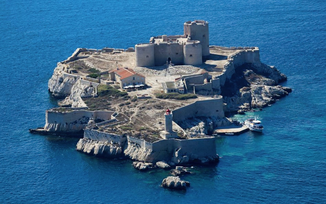 Château d’If on a small island in Marseille, France, with a boat docked nearby.