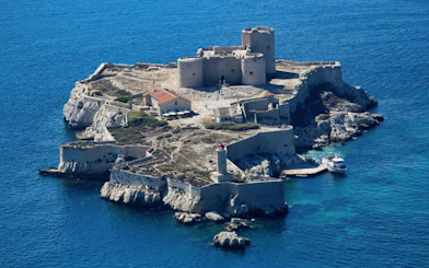 Château d’If on a small island in Marseille, France, with a boat docked nearby.