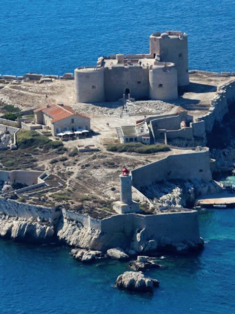 Château d’If on a small island in Marseille, France, with a boat docked nearby.