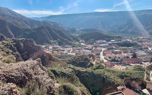 Granada Geopark village view with hikers on a trail through rugged desert landscape.