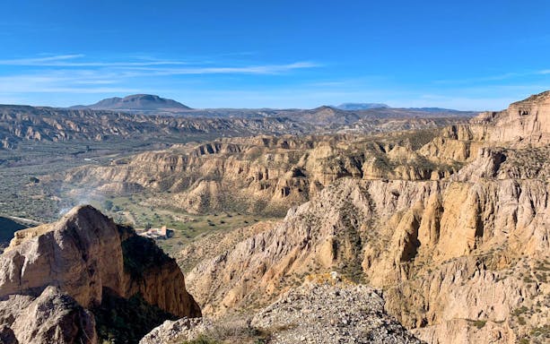 Granada Geopark desert landscape with rugged cliffs and distant mountains.