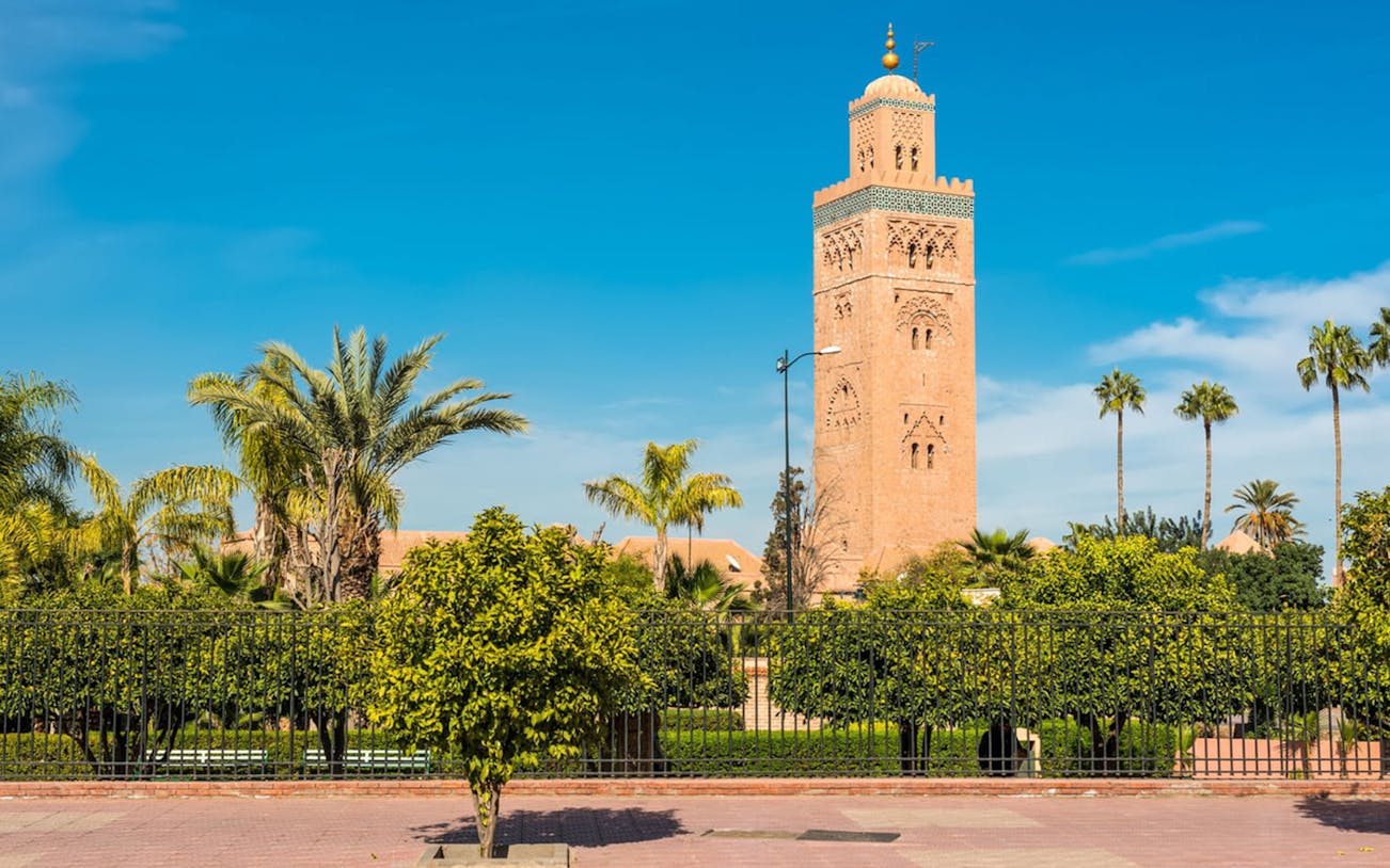 Koutoubia Mosque tower in Marrakesh with surrounding palm trees.