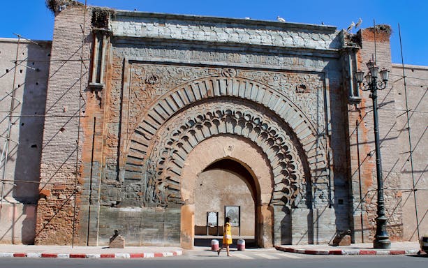 Bab Agnaou gate in Marrakesh with intricate stone carvings and a person walking through.