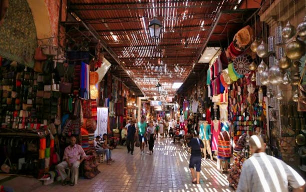 Marrakesh souks with colorful textiles and lanterns in Medina market.