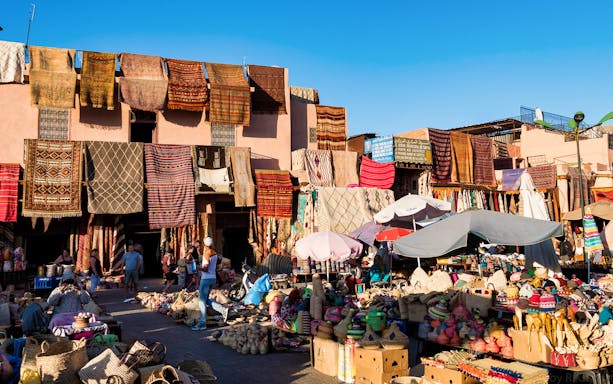 Colorful market stalls and hanging rugs in Marrakesh's Medina.