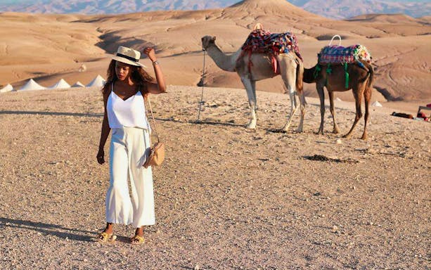 Person walking in Agafay Desert with camels in the background, near Marrakesh.