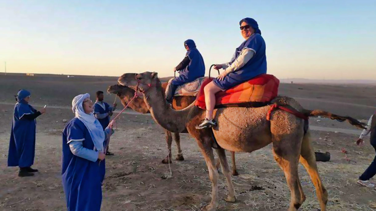 Camel ride in Agafay Desert with tourists in traditional attire, near Marrakesh.