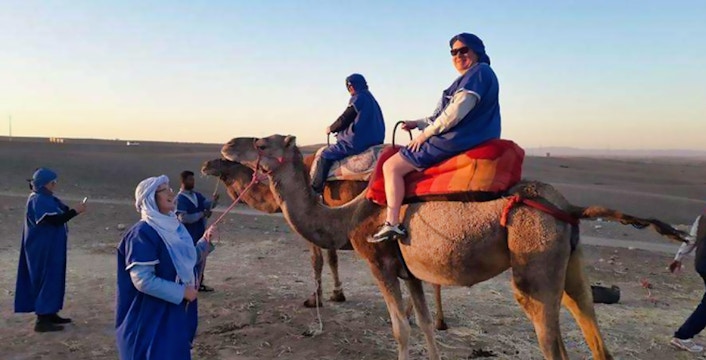 Camel ride in Agafay Desert with tourists in traditional attire, near Marrakesh.