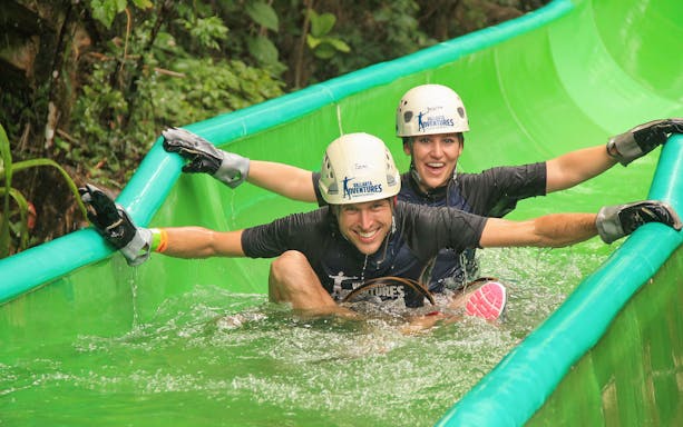 Two people enjoying a water slide in Banderas Bay jungle adventure.