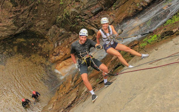 Zip lining adventure in Banderas Bay jungle with participants on a rock face.