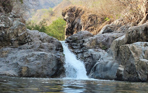Waterfall surrounded by rocky cliffs near Jorullo Suspended Bridge ATV tour location.