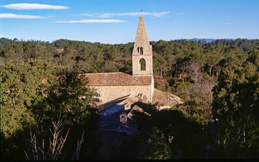 Abbaye du Thoronet surrounded by trees under a clear blue sky.