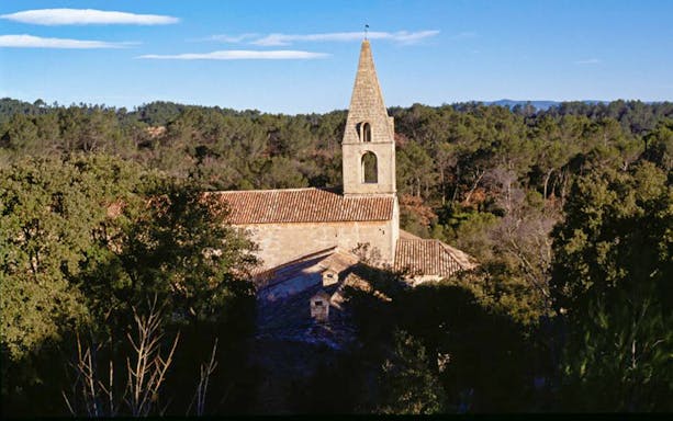 Abbaye du Thoronet surrounded by trees under a clear blue sky.
