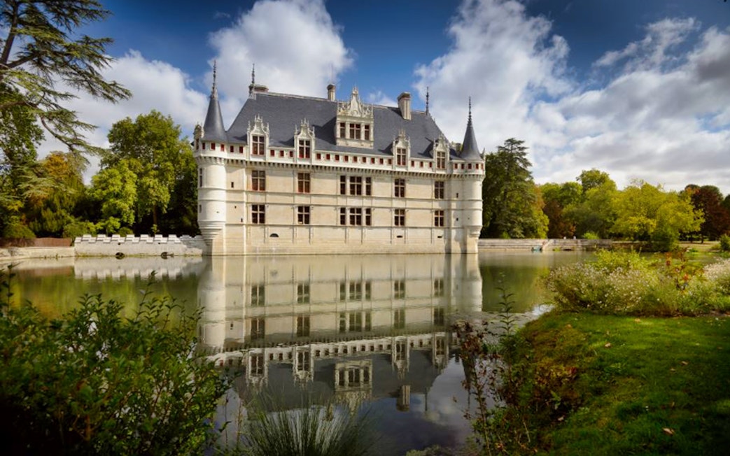 Château of Azay-le-Rideau reflecting in a tranquil moat, surrounded by lush greenery.
