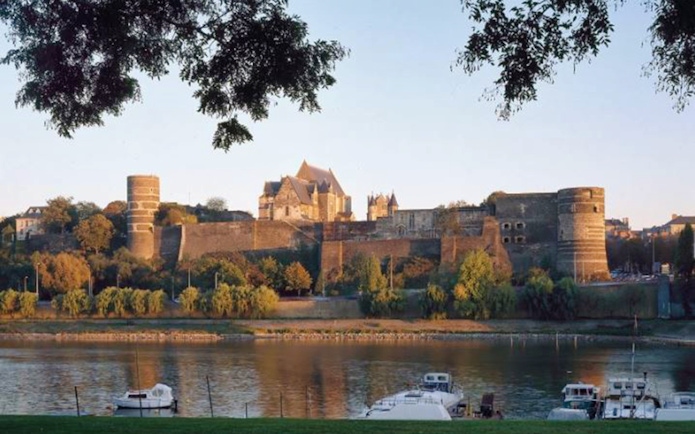 Panoramic view of Angers Castle with river and boats in foreground, France.