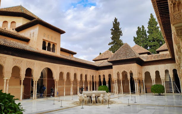 Courtyard of the Lions at Alhambra, Granada, featuring intricate arches and lion fountain.