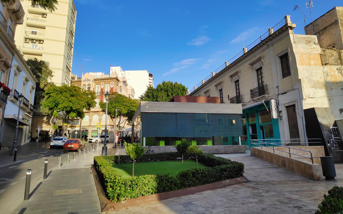 Almeria city center street view with historic buildings and outdoor dining area.