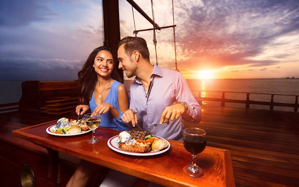 Couple dining on a sunset cruise in Cancun with Go Cancun Pass.
