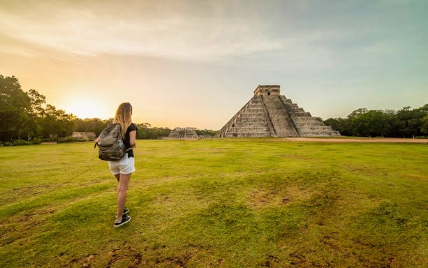 Traveler exploring Chichen Itza pyramid at sunset, Yucatan, Mexico.