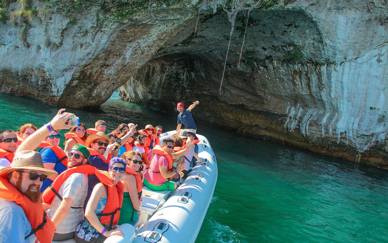 Tourists on a boat near a rocky arch in Banderas Bay during a sea safari tour.