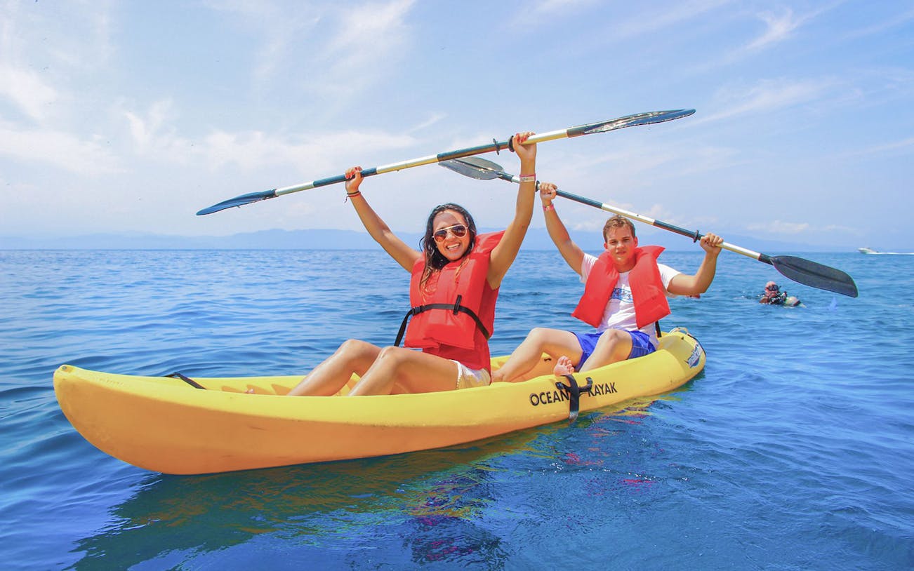 Two people kayaking at Las Caletas Beach, Mexico, wearing life vests.