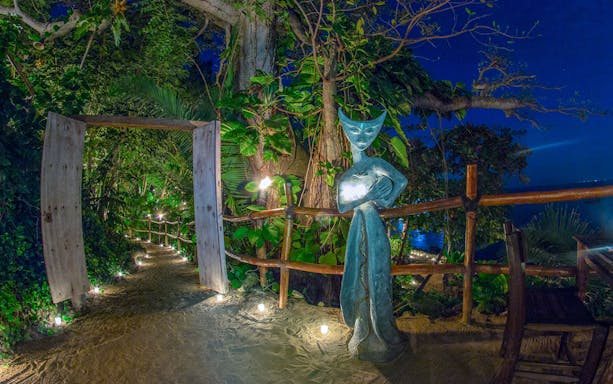 Pathway lit by candles with a statue at Rhythms of the Night Dinner Show, Mexico.