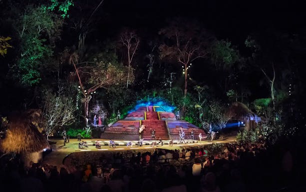Outdoor performance at Rhythms of the Night VIP Dinner Show, featuring dancers on a lit stage surrounded by jungle.