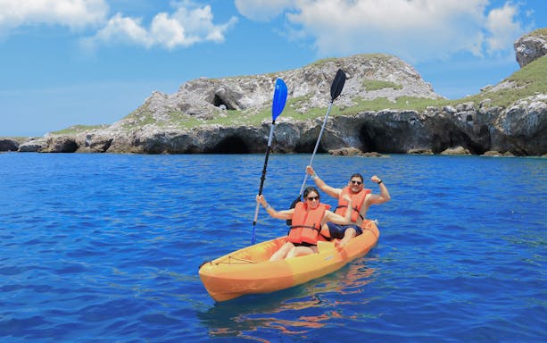 Kayakers in orange vests paddle near rocky Islas Marietas, Puerto Vallarta.