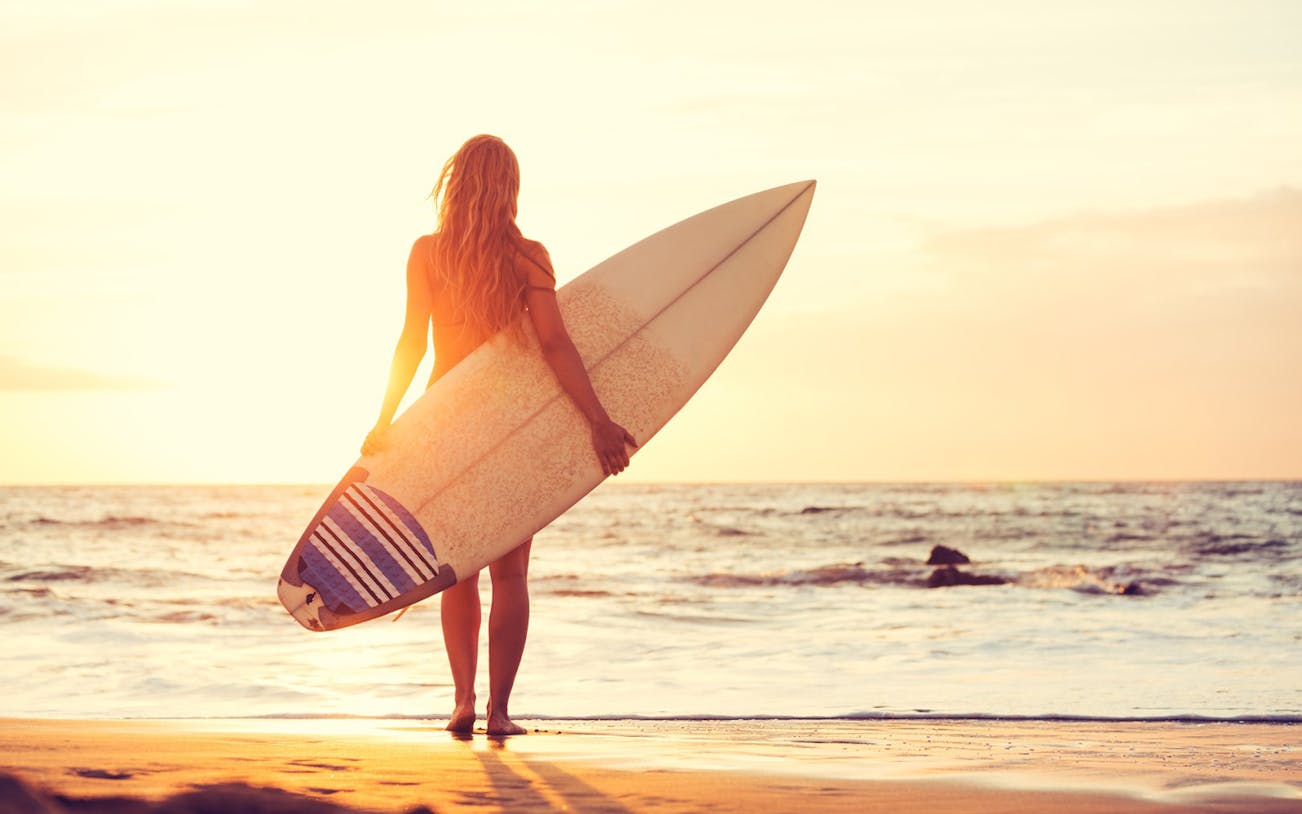 Surfer holding a board at sunset on Sayulita Beach, Mexico.