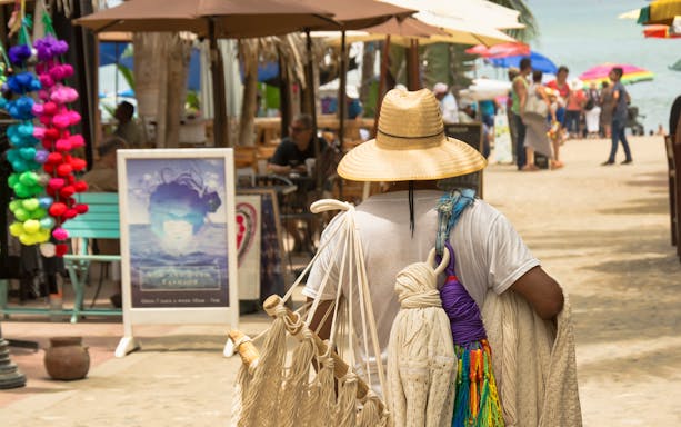 Vendor with woven goods walking in Sayulita Beach town market, Mexico.