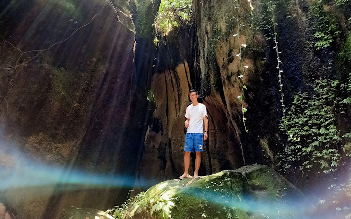 Man standing in a sunlit cave with lush greenery, Bali Instagram Private Tour.