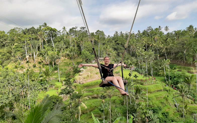 Person on a swing over lush rice terraces in Bali, Indonesia.