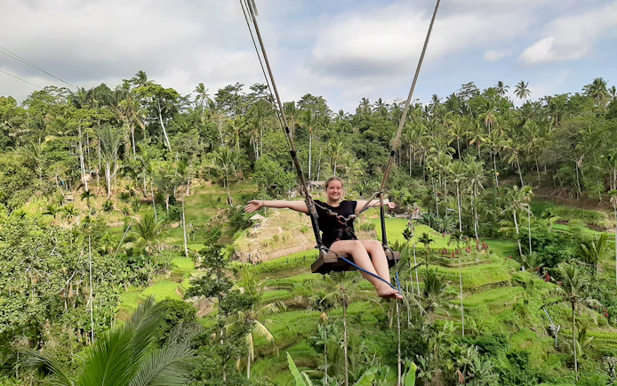 Person on a swing over lush rice terraces in Bali, Indonesia.