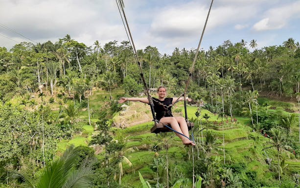 Person on a swing over lush rice terraces in Bali, Indonesia.