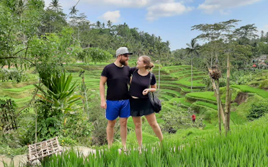 Couple standing in front of Tegallalang Rice Terraces, Bali, during a scenic Instagram tour.