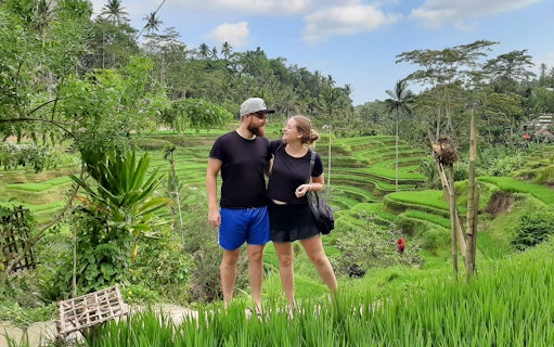 Couple standing in front of Tegallalang Rice Terraces, Bali, during a scenic Instagram tour.