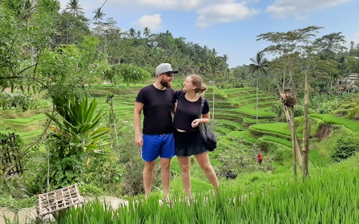 Couple standing in front of Tegallalang Rice Terraces, Bali, during a scenic Instagram tour.