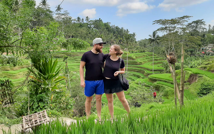 Couple standing in front of Tegallalang Rice Terraces, Bali, during a scenic Instagram tour.