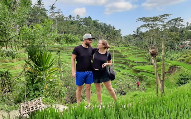 Couple standing in front of Tegallalang Rice Terraces, Bali, during a scenic Instagram tour.