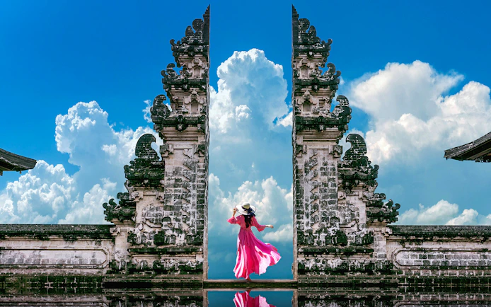 Woman in pink dress at Bali's Lempuyang Temple, known as the Gates of Heaven.