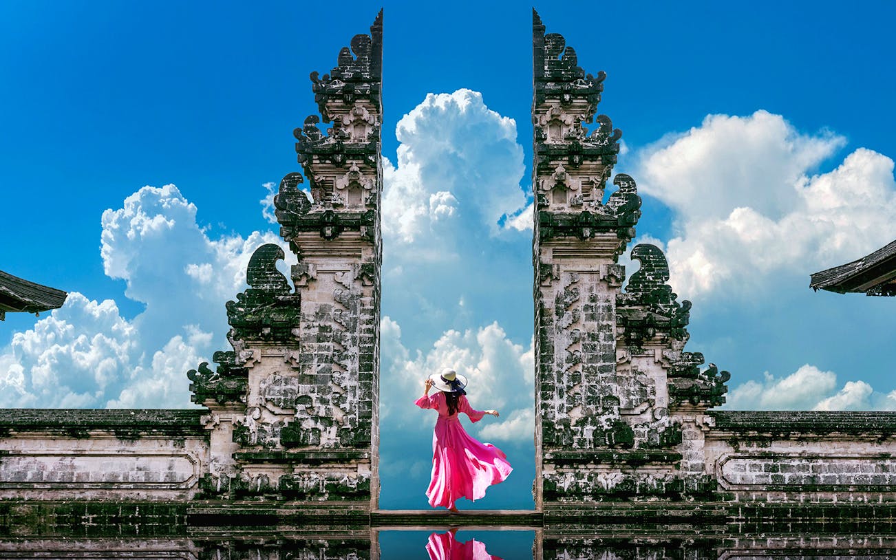 Woman in pink dress at Bali's Lempuyang Temple, known as the Gates of Heaven.