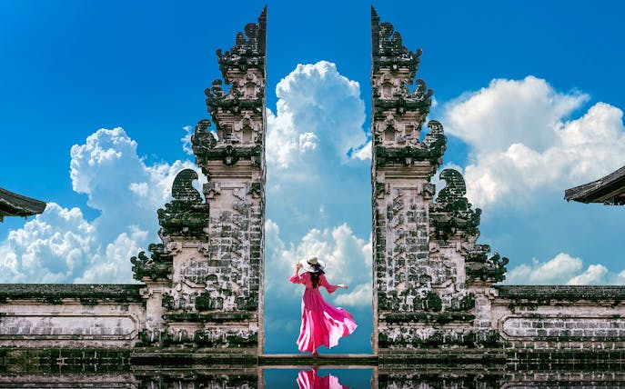 Woman in pink dress at Bali's Lempuyang Temple, known as the Gates of Heaven.