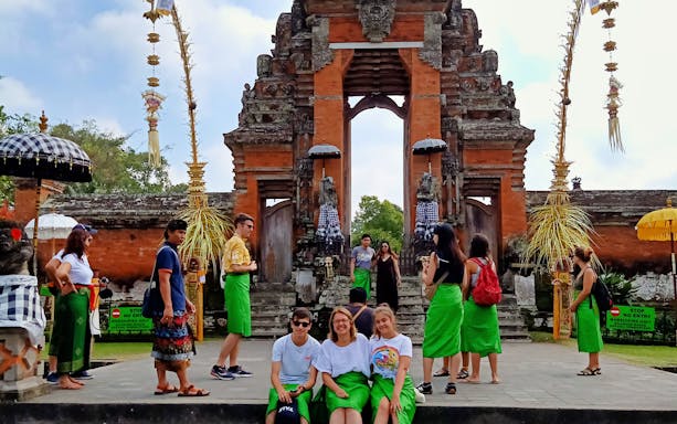 Balinese temple entrance with tourists in traditional sarongs, Bali Private Bedugul, Tanah Lot Sunset Tour.