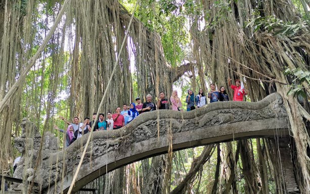 Group on a stone bridge in Ubud's Monkey Forest surrounded by lush trees.