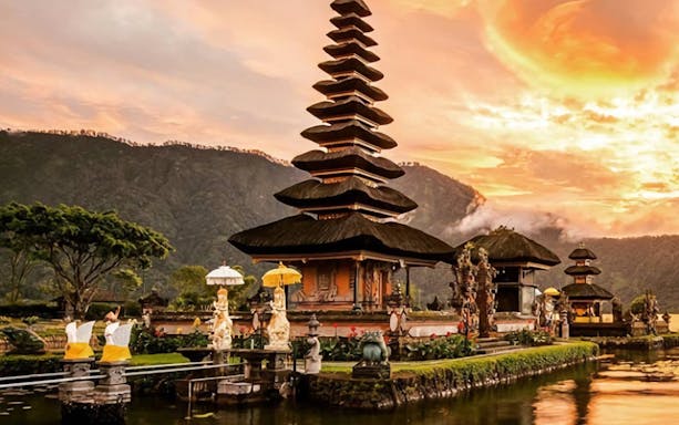 Ulundanu Beratan Temple at sunrise in Bali with mountains in the background.